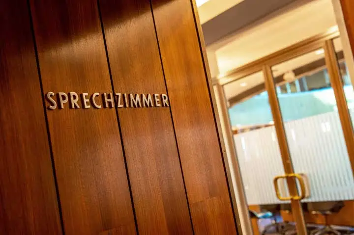 Holzvertäfelung mit dem Schriftzug „Sprechzimmer“, im Hintergrund eine Glastür.
